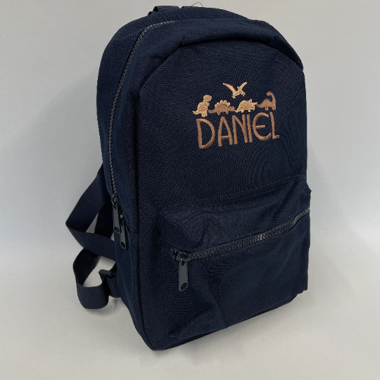 This is a navy blue backpack with a main zip compartment and a smaller pouch on the front. The bag is embroidered with five dinosaurs in two different shades of brown. The bag also has a name embroidered. These backs are a great size for nursery or primary school.