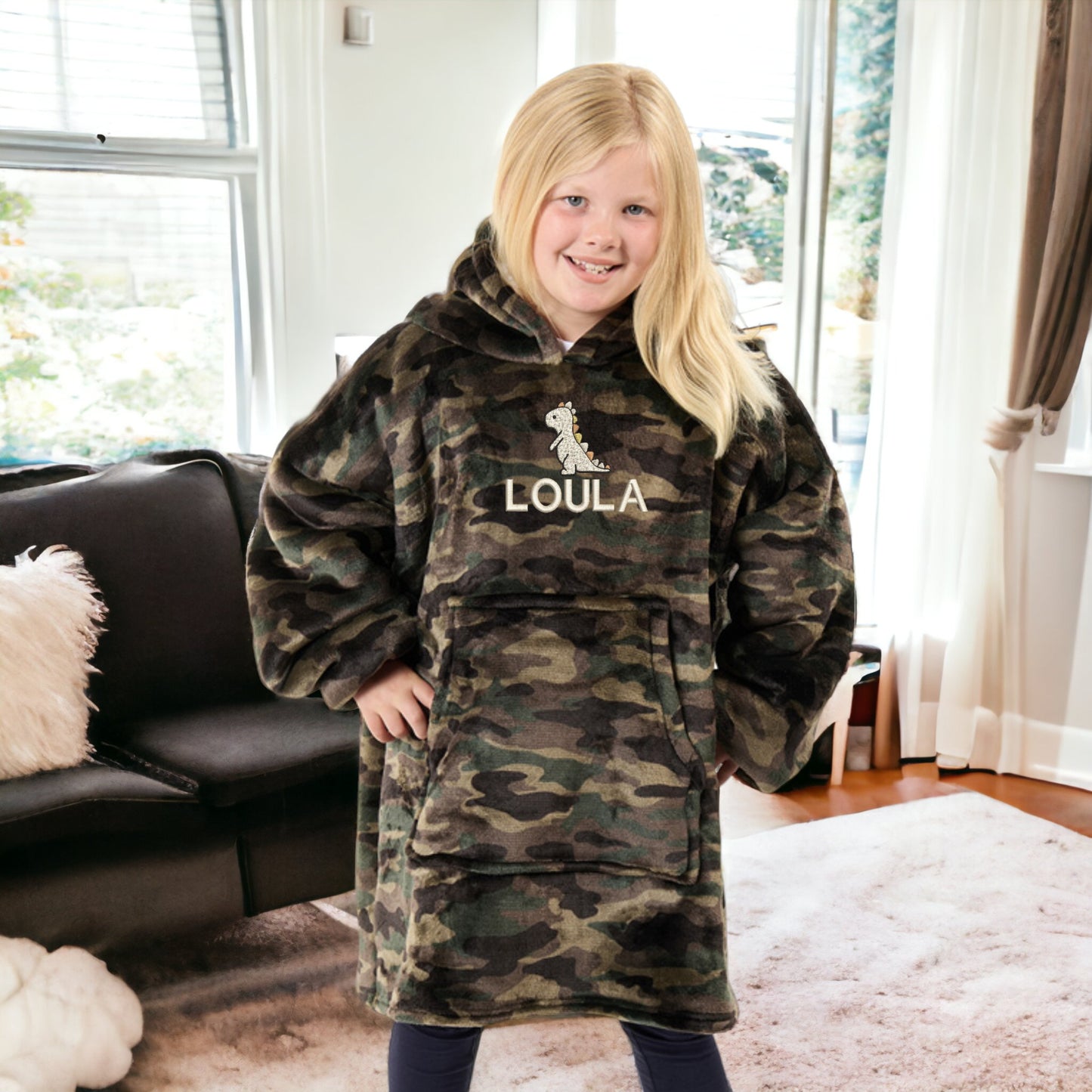 This is a picture of a girl wearing a fleece and sherpa oversized hoodie. The hoodie is embroidered on the front with a little cream dinosaur and a name below it. These are available in children's and adult sizes and different colours too.