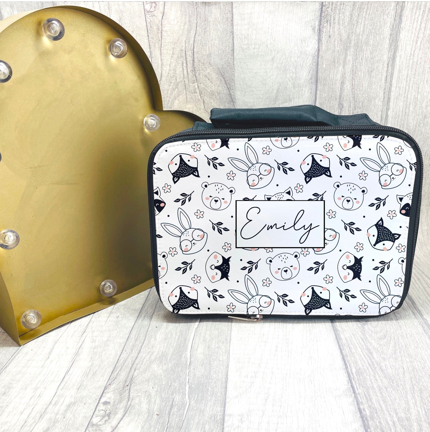 This is a black insulated lunch bag with a full zip closure and a carry handle at the top. The front of the bag is printed with a full boho animals pattern and a child’s name in the middle