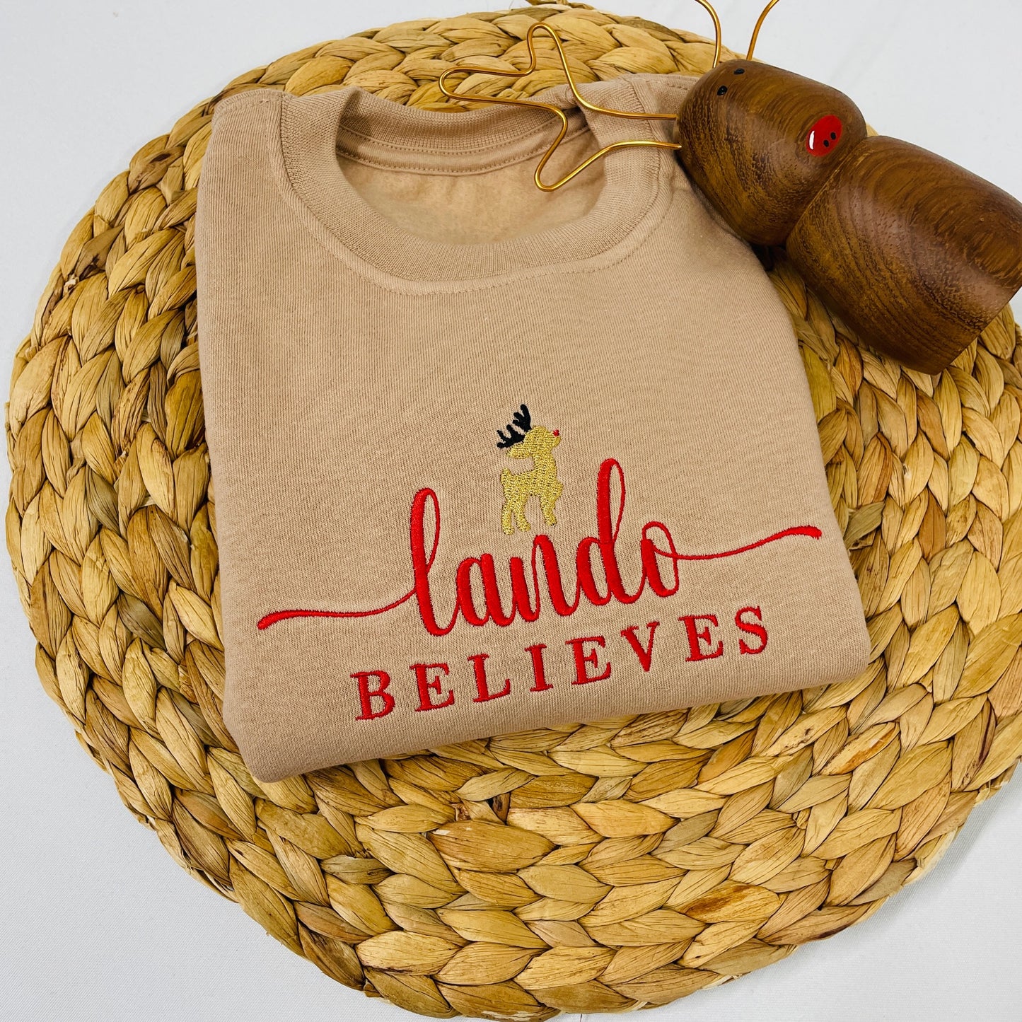 This is a taupe sweater with a little reindeer with a red nose embroidered at the top. Below the reindeer is a name and the word ‘believes’. Get into the Christmas spirit with a personalised sweater