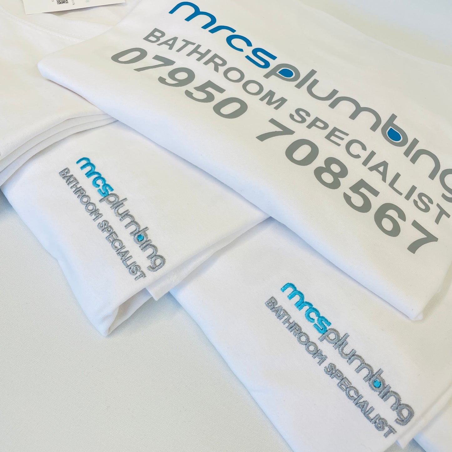 This is a bundle of white 100% cotton crew neck tshirt for men and women. The tshirt has an embroidered logo on the front left breast with a bigger logo and contact details printed on the back in vinyl.