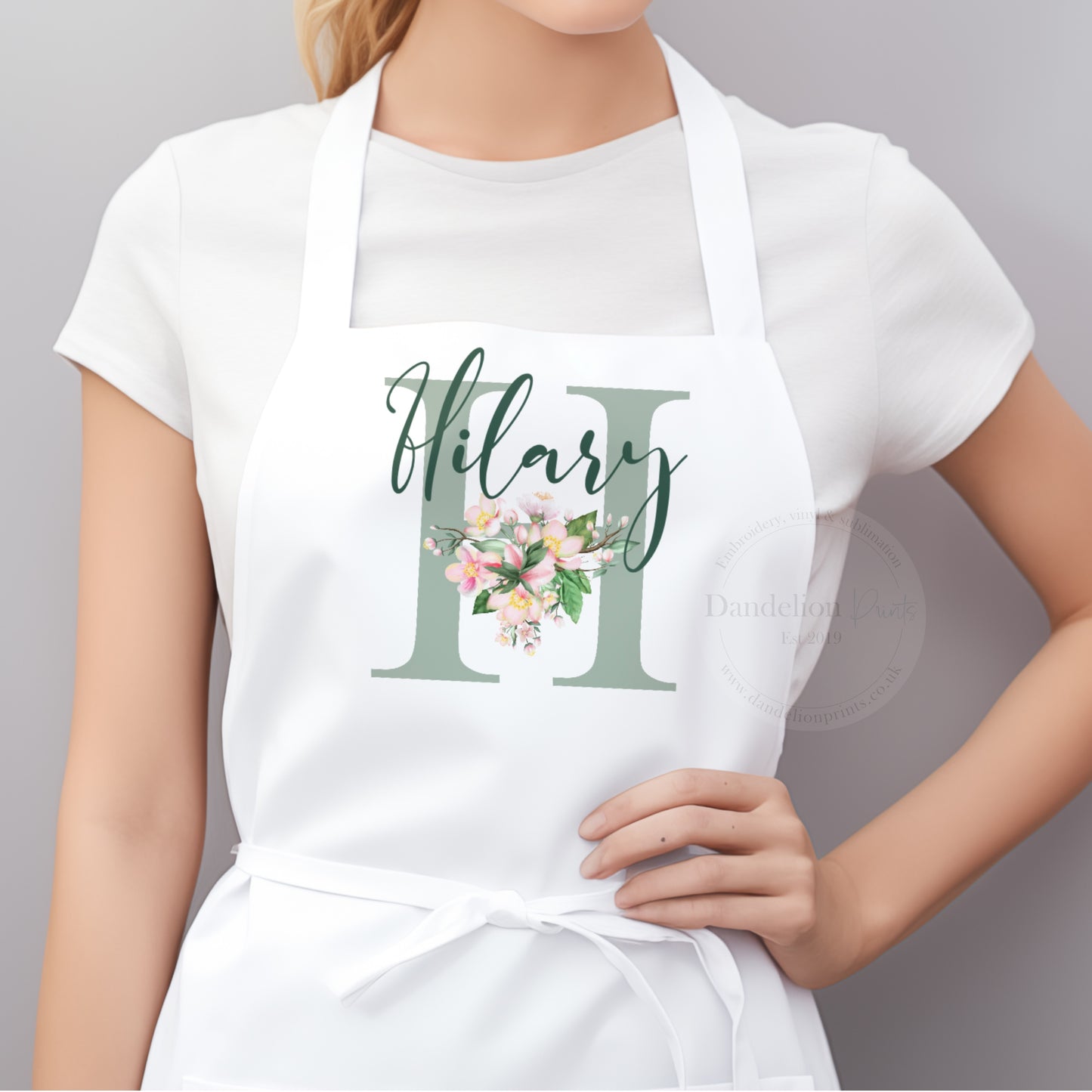 This is a ladies apron printed with a sage initial and pretty pink flowers. A name is also printed across the initial. Perfect personalised gift idea for those that love to bake and create.
