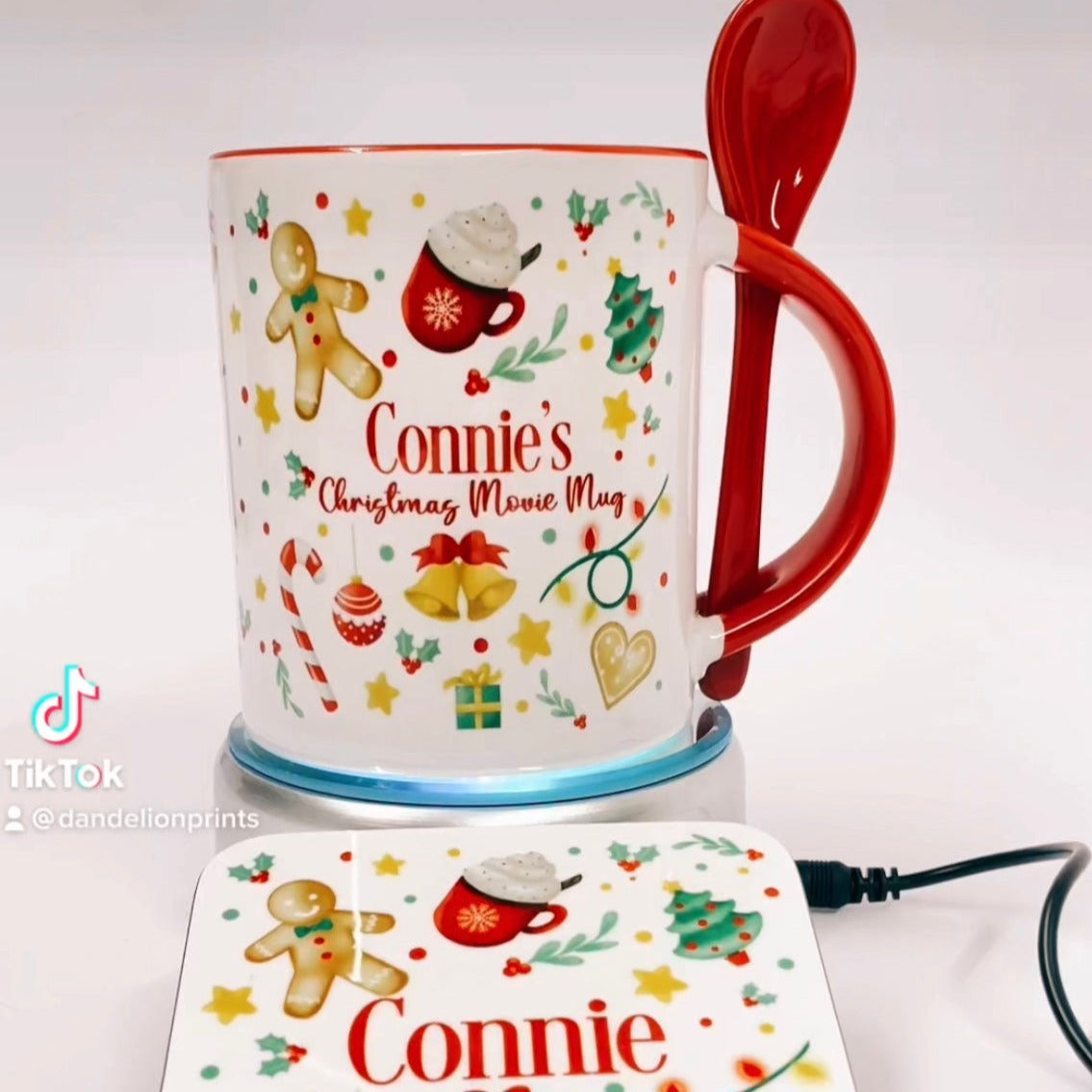 This is a white mug with a red handle and red inner. This mug has a special slot in the handle to hold a matching red ceramic spoon. The mug is printed with many different christmas ornaments wrapped all the way around. The centre of the print has NAME christmas movie mug. Snuggle up with your hot cocoa with a christmas movie and enjoy the festivities