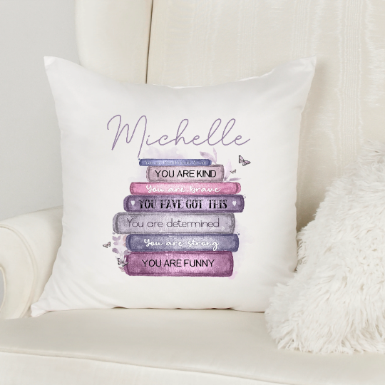 Affirmations velvet cushion 40x40cm. The cushion features a pink/purple stack of books with the words, you are kind, you are brave, you have got this, you are determined, you are strong, you are funny. Use this cushion to remember your self worth.