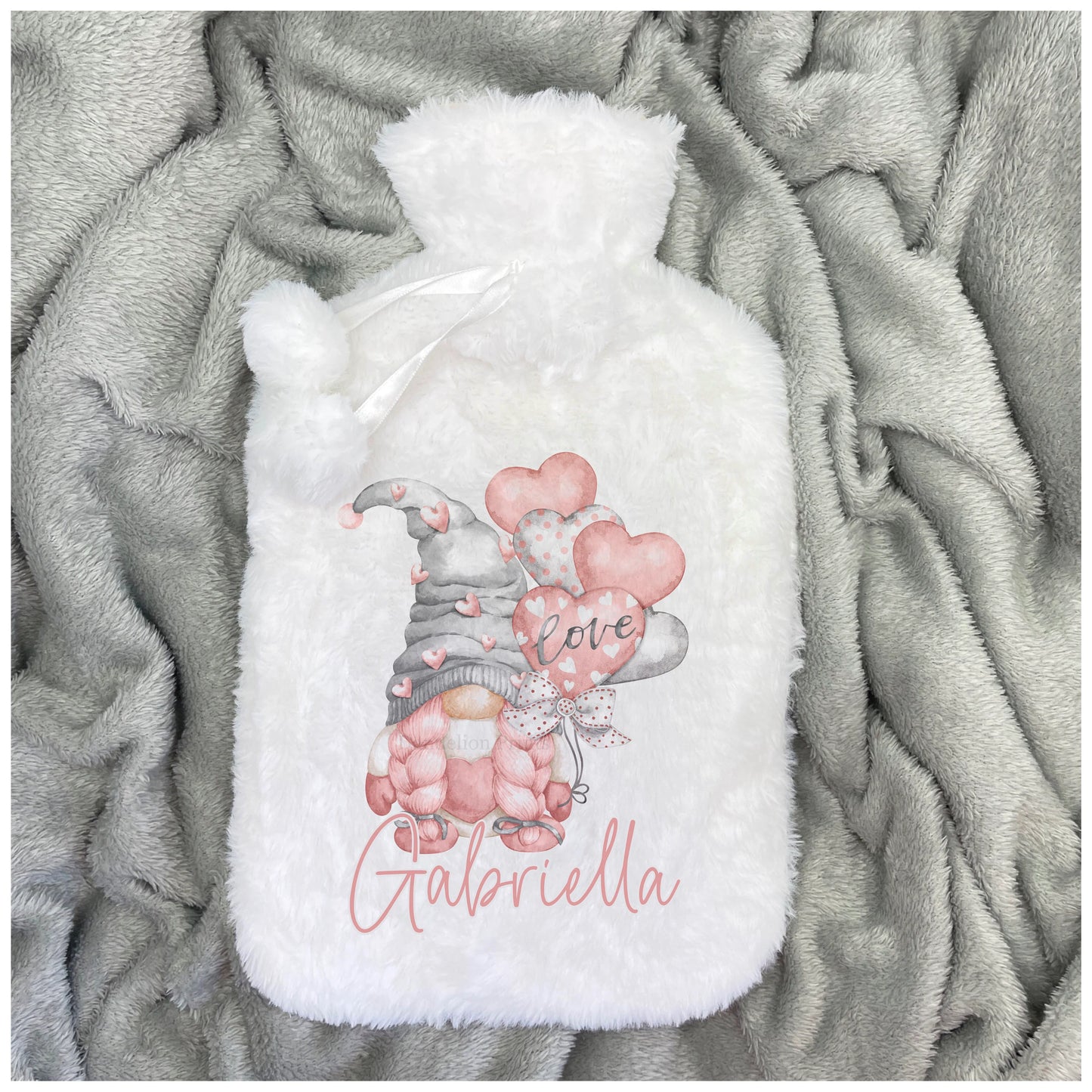 Super soft and fluffy white hot water bottle printed with a lovely pink and grey gonk design. The gonk has a grey hat with pink hearts. It is sitting inside a pink mug. The theme is 'love'. This is also personalised with a name.