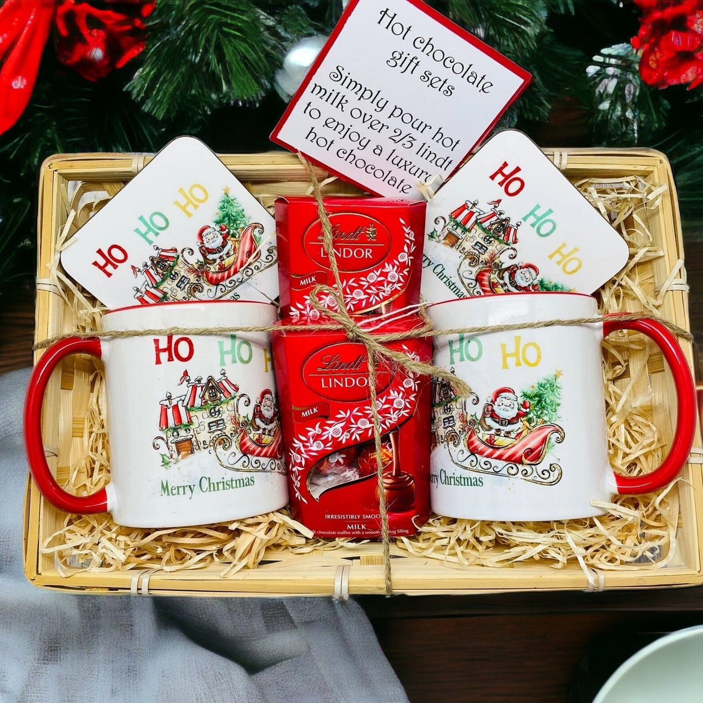 Christmas gift set in a wicker basket filled with a mug, coaster and Lindt chocolates. The design on the mug is Santa on his sleigh heading to a candy cane house to deliver presents. Ideal Christmas Eve gift. Stocking filler.
