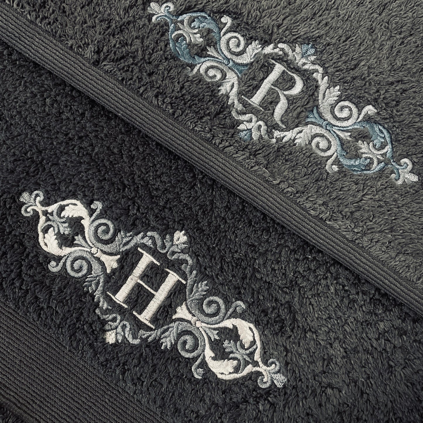 This picture shows off two beautifully embroidered dark grey hand towels. These towels have a luxury appearance and feel. They are embroidered with a stunning royal flourish with an initial in your choice of thread colour. Lovely couples gift.