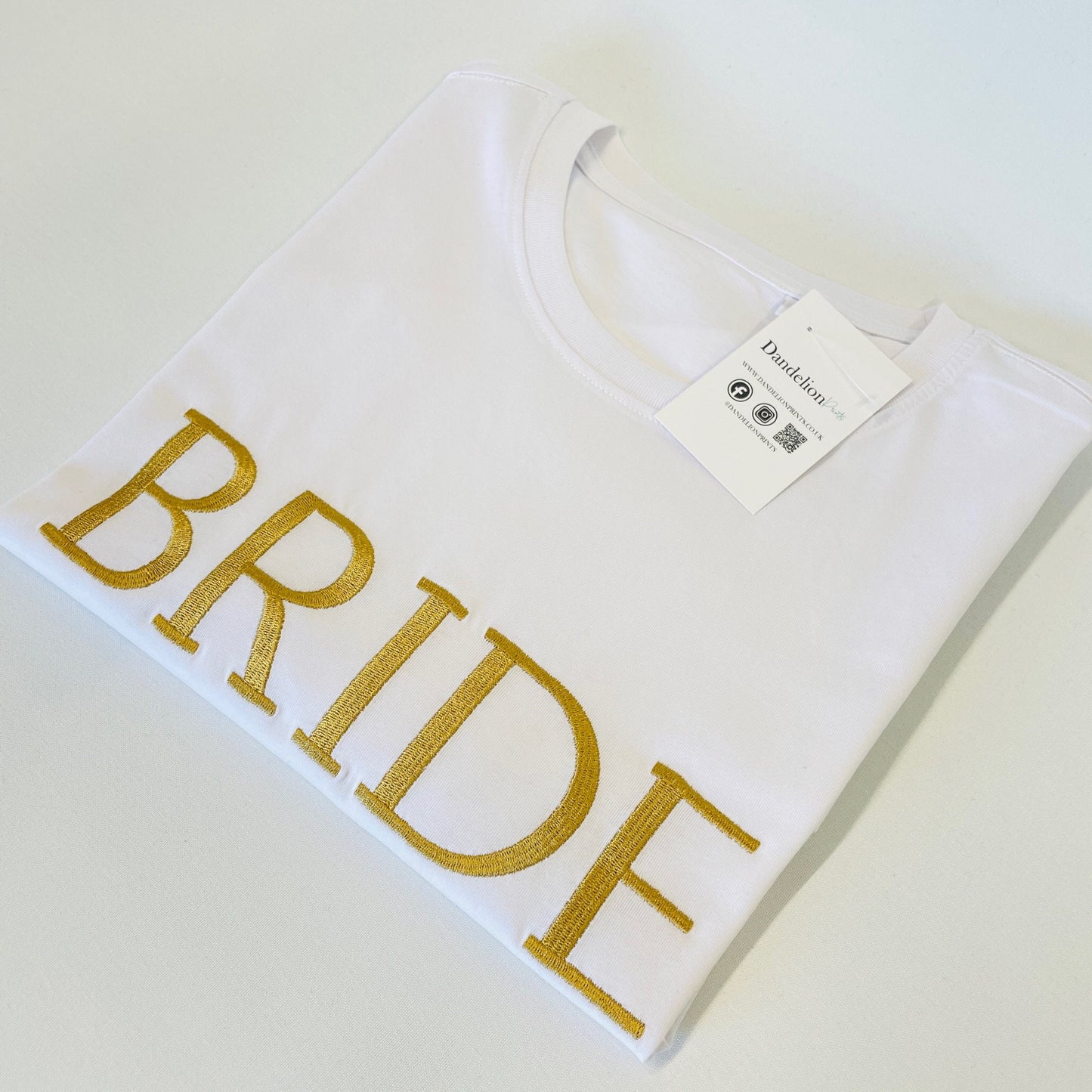 This is a white organic t-shirt with BRIDE embroidered across the chest in gold. These t-shirts are available in many sizes