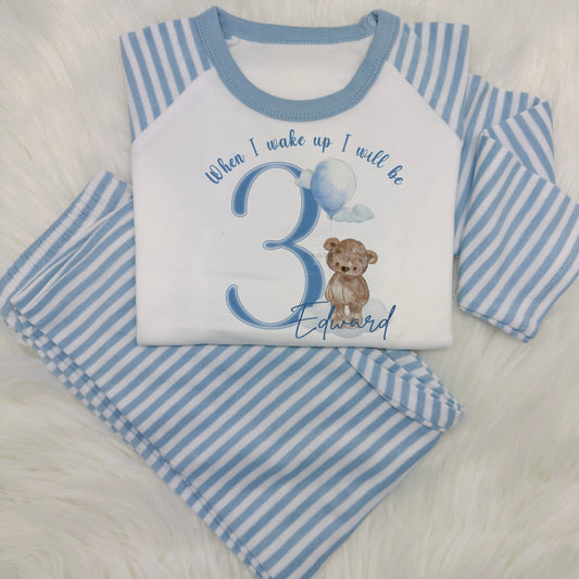 Adorable kids pyjamas featuring blue sleeves and legs.

The front showcases a sweet bear holding birthday balloons, with the message 'When I wake up I will be [Child's age].' Perfect for a personalised birthday eve gift.


The number is changed to your requirements - simply enter your child's age and name in the personalisation box.

These are super soft, long sleeve top and bottom and 100% cotton.
Please take a look at the size guide in the photos before ordering.