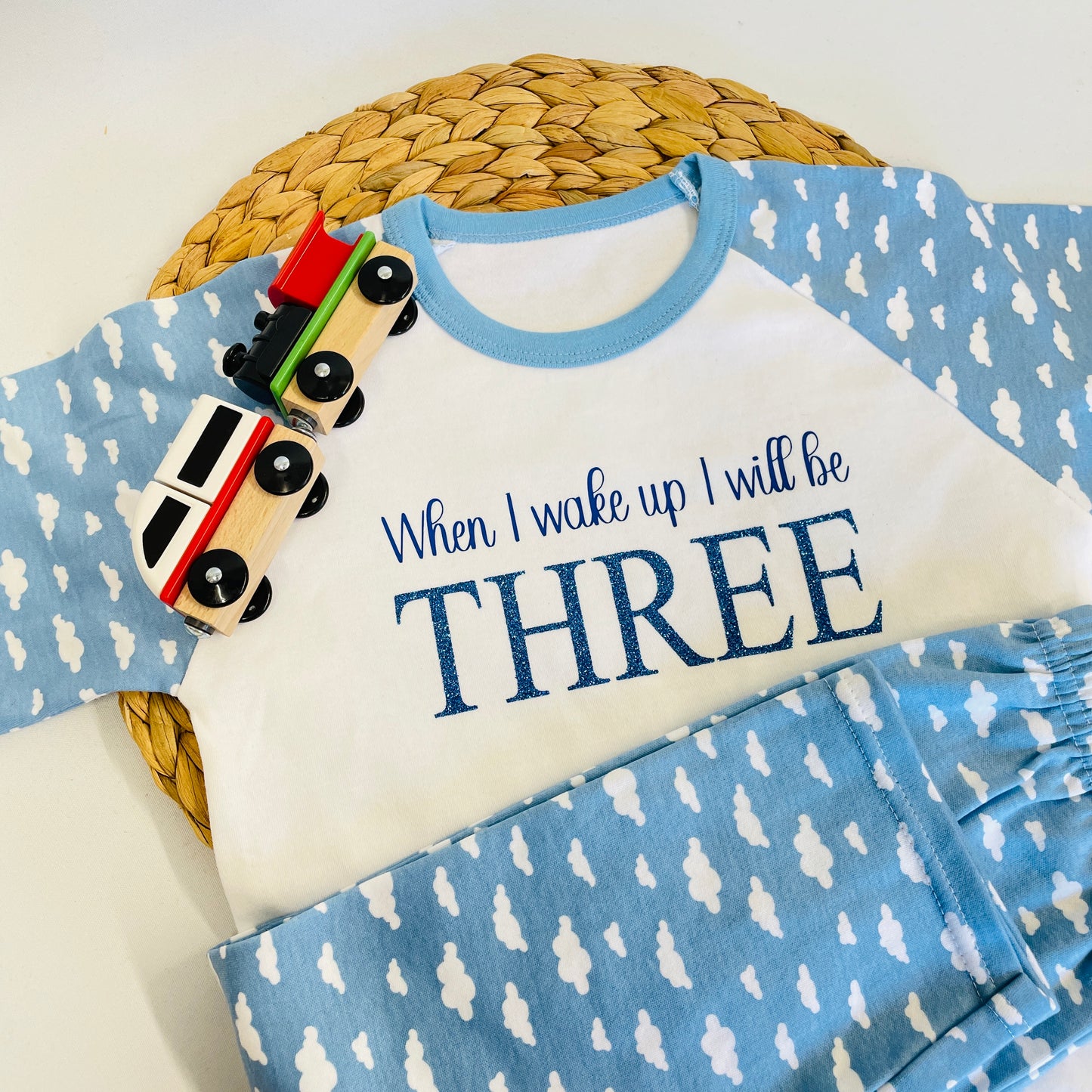 These are 100% cotton pyjamas. The top is long sleeve with a blue clouds print. The bottoms are also blue cloud print. The top has written in blue When I wake up I will be, with blue glitter THREE below it.