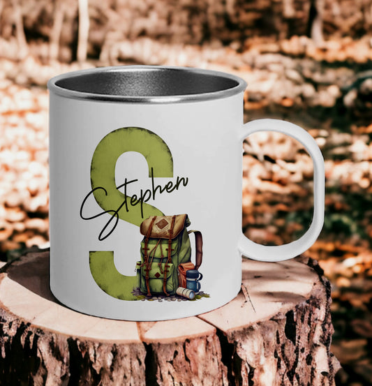 This is a smash proof mug printed with a rusty green initial sitting behind a traveller or hikers backpack. A name is printer across the middle of the design. These mugs are polymer and steel combined making them great for explorers