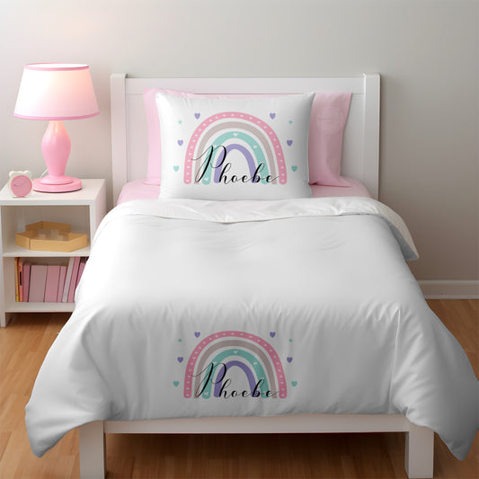 This a girls bedroom with a white duvet cover and pillow. The cover and pillow are both printed with a pastel rainbow and personalised with a name too. The covers are super soft and luxury feel. Perfect for young girls or teens.