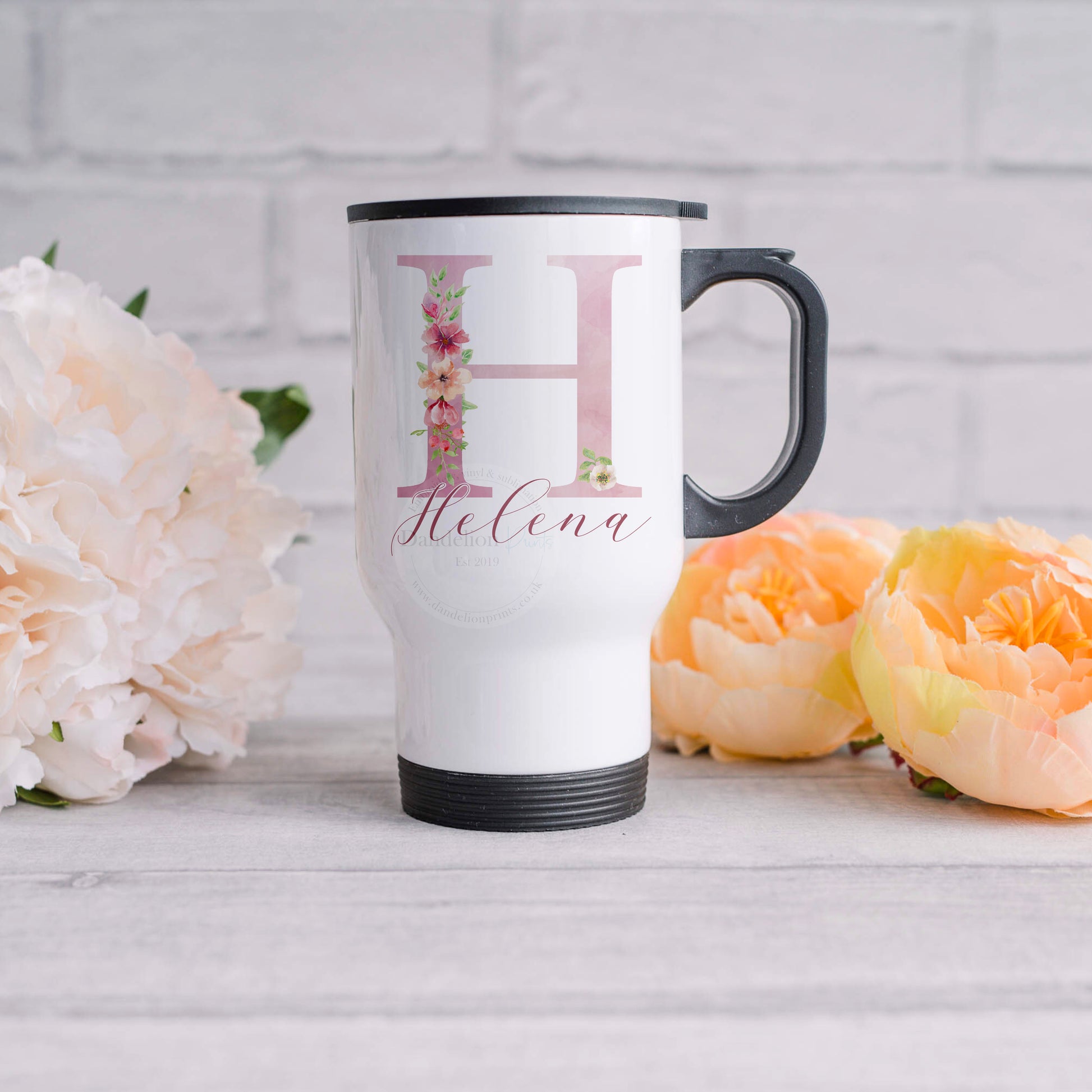 This is a white metal travel mug printed with a pretty pink initial covered with flowers. A name is also printed in darker pink across the bottom. These travel mugs are great for those on the go and didnt get the morning cuppa at home