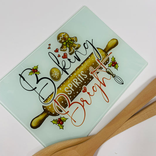 This is a glass christmas chopping board or worktop saver. This is printed on the glass with a cute christmas baking image consisting of holly, ginger bread, cookies and a rolling bin. Baking spirits bright is printed within the design. Brighten up the kitchen this christmas