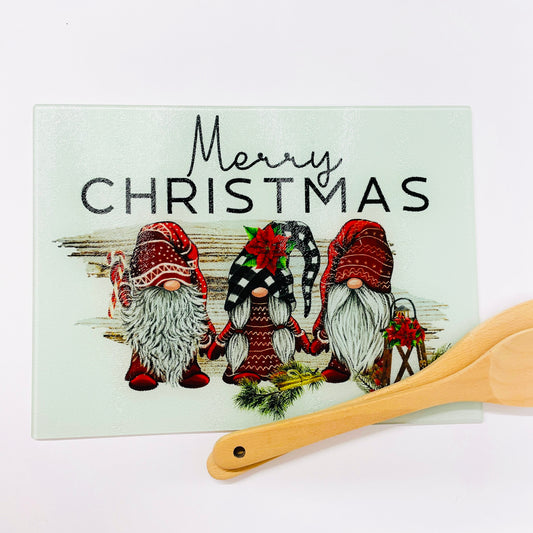 Merry Christmas chopping board printed with three red gnomes. The chopping board is printed on the reverse of the glass to save potential damage to the image