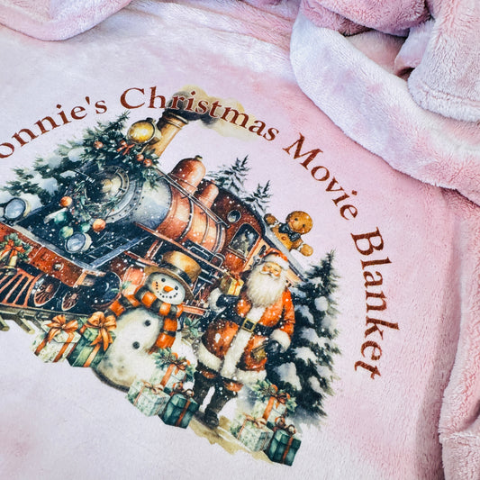 This is a blanket available in pink, grey or cream. The blanket is printed with a big christmas scene with santa and a train. Curved across the entire image is your name with Christmas Movie Blanket. Snuggle up and watch christmas movies.