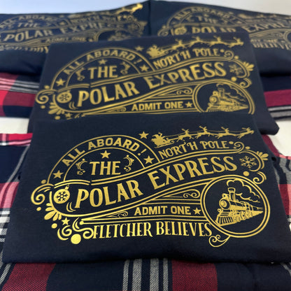 All aboard the Polar Express! Matching family outfits featuring a navy tshirt and tartan red trouser. The tshirt is vinyl printed in gold with an eye catching polar express - north pole design. personalised with a name too