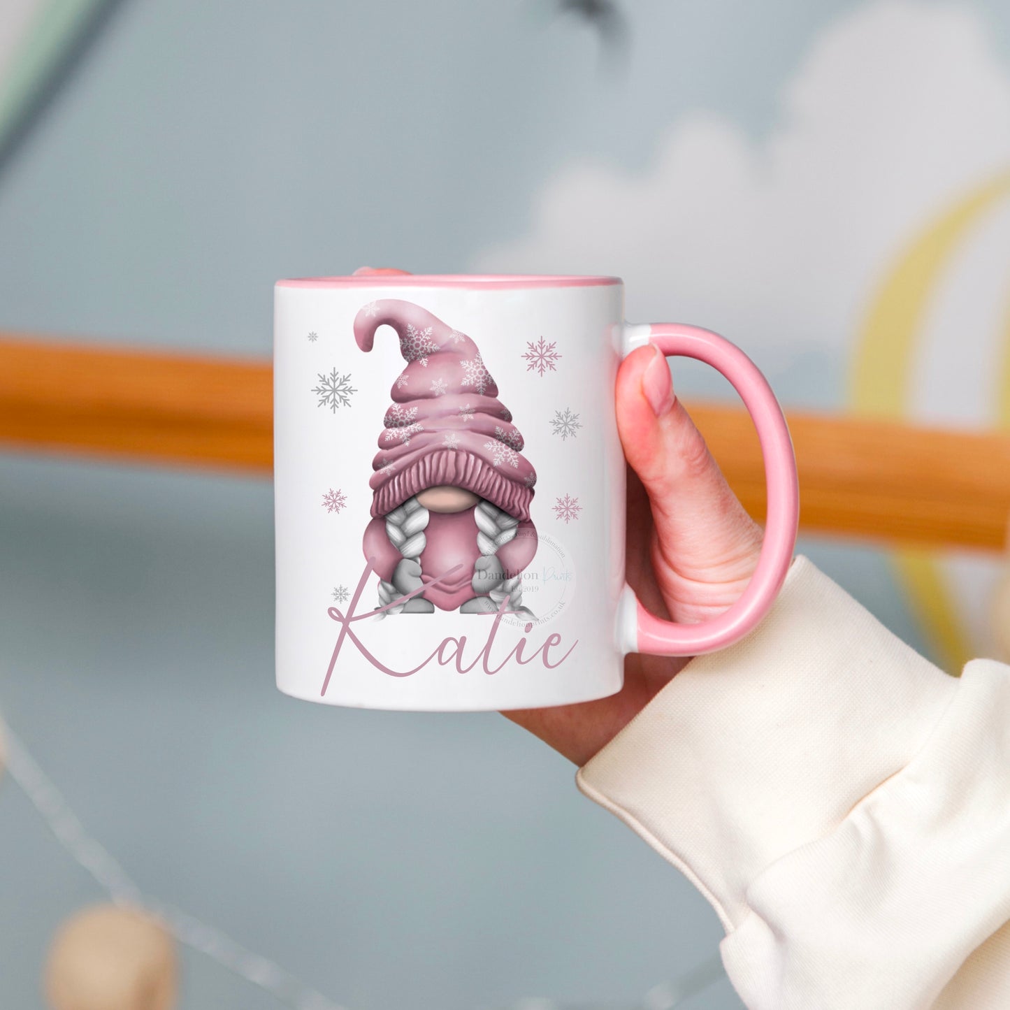 The mug has pink inner and handle. It is printed on the lid with a festive pink gonk with snowflakes on its hat. The mug is also personalised with a name in pink below the gonk. Use this mug to enjoy your tea, coffee or hot chocolate.