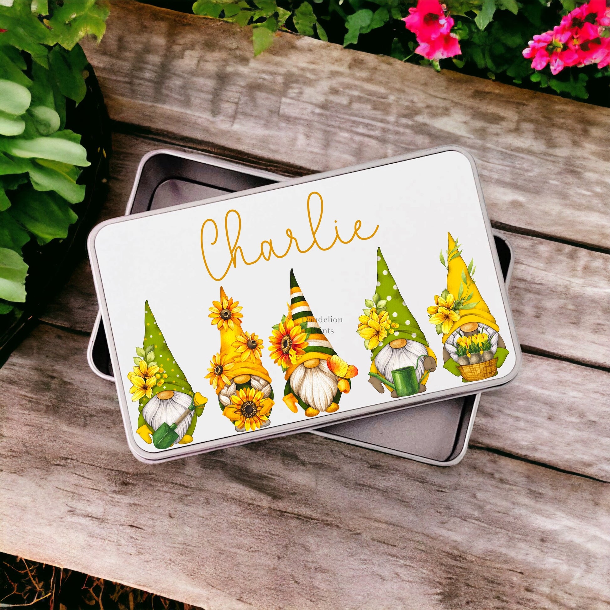 This is a metal storage tin printed with a line up of sunflower gonks. Each gonk has its own pattern from spotty to stripy all yellow and green. The tin is also personalised with a name at the top