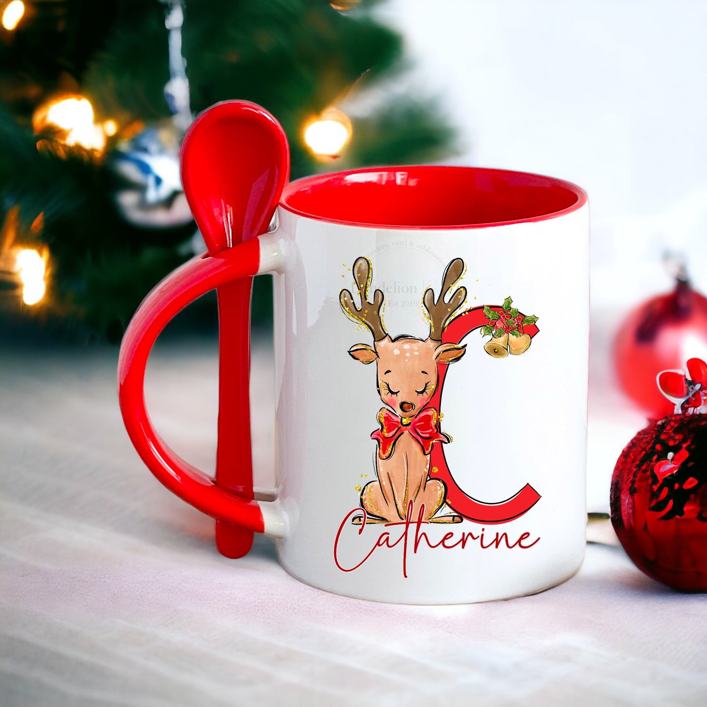 This is a white mug with a red inner and handle. The handle holds a matching ceramic spoon. The mug is printed with a glittery reindeer with an initial and personalised with a name too. Christmas gift or stocking filler idea.