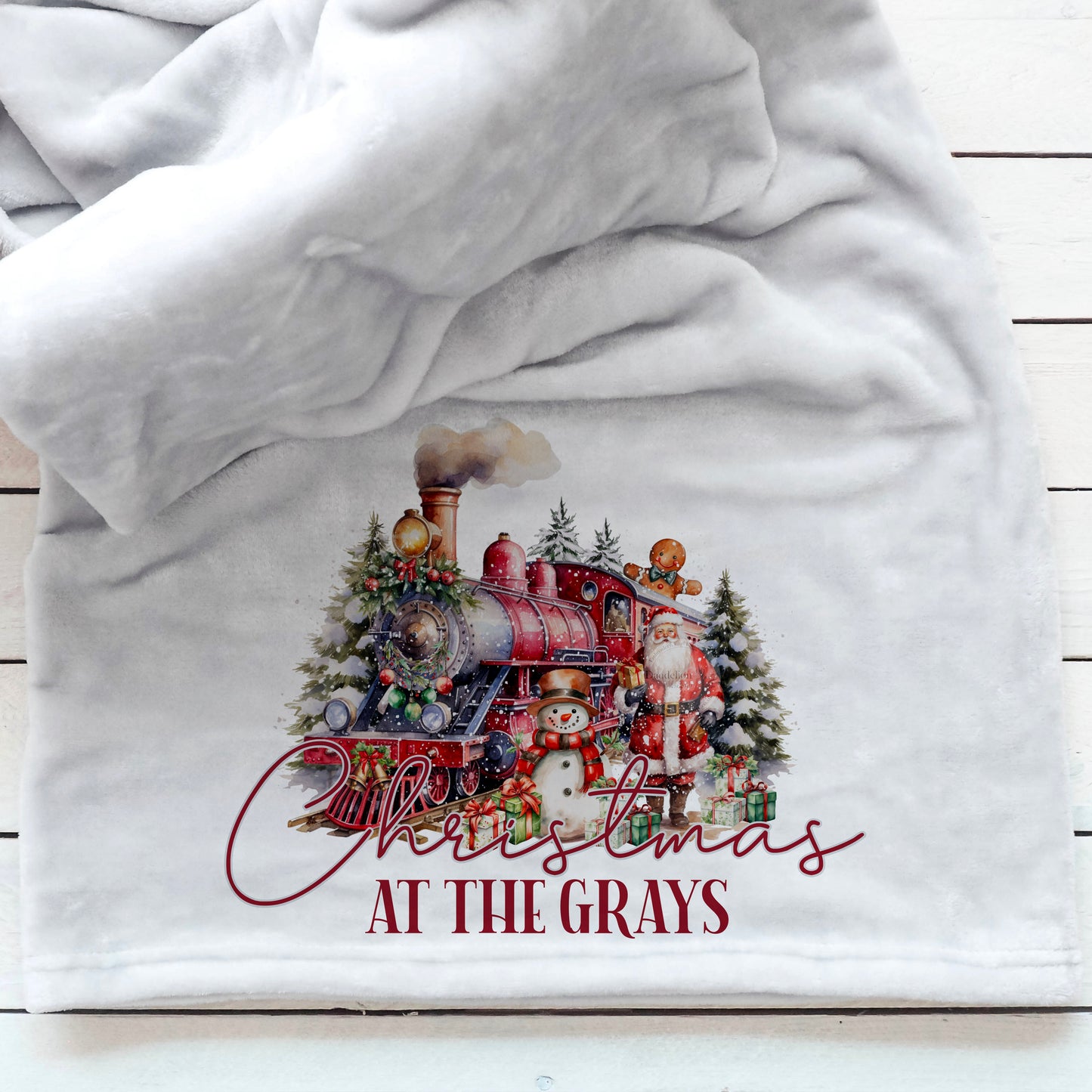 This is a beautiful Christmas blanket perfect for snuggling and watching a Christmas movie. The blanket is printed with a vintage polar express with Santa and a snowman standing next to it. Christmas at the YOUR NAME is printed below the image