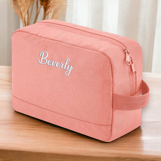 This is a pink wash bag with a zip top closure. The bag has two compartments inside, one is a pocket and the other is a zip.  On the front of the bag, embroidered elegantly is a name. Personalised ladies toiletries wash or travel bag gift idea