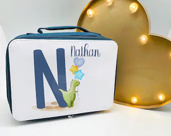 This is a navy blue insulated, zipped lunch bag with a carry handle at the top. Printed on the front is a cute watercolour green dinosaur with balloons next to a blue initial. There is a name printed above the Dino. Personalised school lunch bag