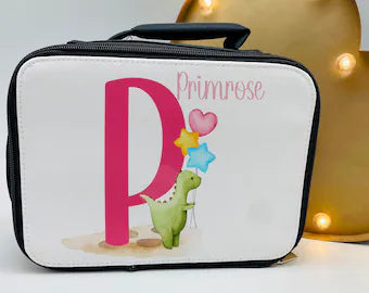 This is a black insulated, zipped lunch bag with a carry handle at the top. Printed on the front is a cute watercolour green dinosaur with balloons next to a pink initial. There is a name printed above the Dino. Personalised school lunch bag