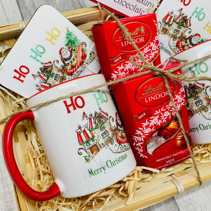 Christmas gift set in a wicker basket filled with a mug, coaster and Lindt chocolates. The design on the mug is Santa on his sleigh heading to a candy cane house to deliver presents. Ideal Christmas Eve gift. Stocking filler.