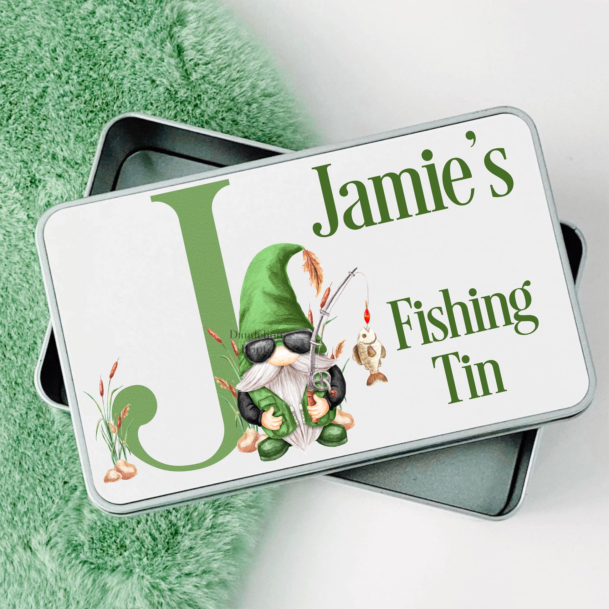 This is a metal tin printed with a gonk fishing and an initial. This also has a name and a description of what is inside the tin. All text can be edited. The main colour of the printing is green.