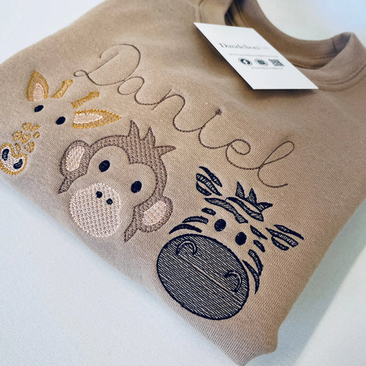 This is a lovely childrens embroidered sweater. The design on the front features a giraffe, monkey and zebra with a name all in a sketch stitch style. The jumper is fleece lined