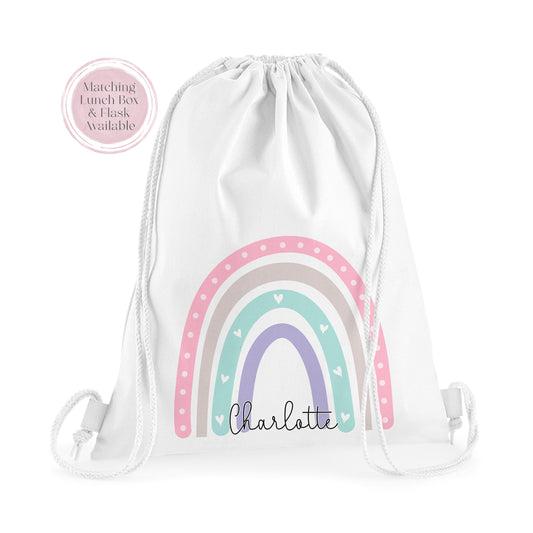 Image of a white PE bag with white drawstrings and a printed image to the front.  The image is of a pastel coloured rainbow with the name Charlotte