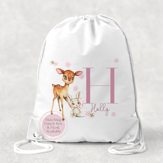 Image of a white PE bag with white drawstrings and a printed image to the front.  The image is of an initial H with the name Holly in pink and a pair of woodland animals to the side. There is a deer and rabbit.