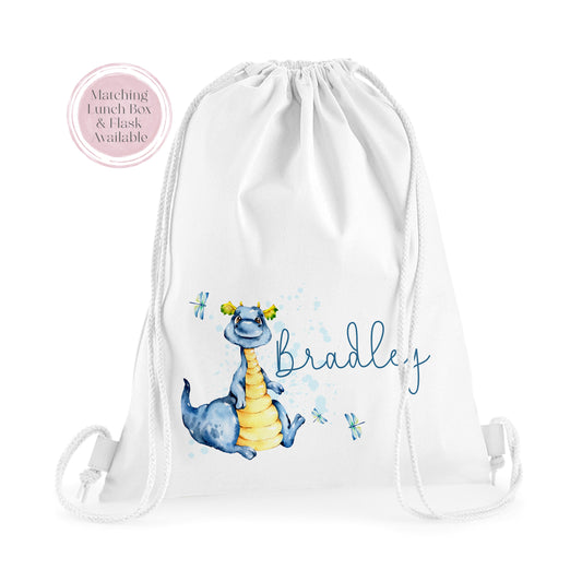 Image of a white PE bag with white drawstrings and a printed image to the front.  The image is of a blue dragon sat down with dragon flies flying and the name Bradley in blue to the side.