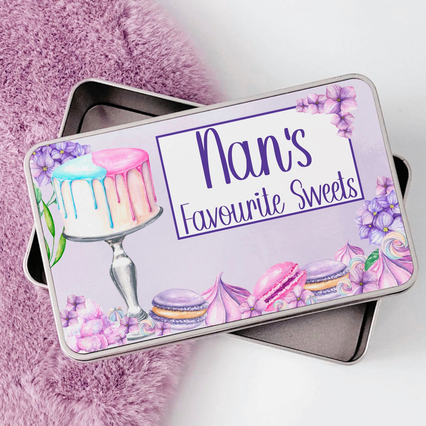 This is an aluminium tin printed with a purple sweets design. The design consists of lots of sweets including macaroons, pavlova, pink and blue drip cake and pretty florals. The text on the tin says ‘Nan’s Favourite Sweets’