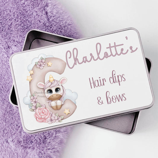 Super cute rectangle metal tin. The tin is printed with a unicorn initial decoratd with flowers and stars in purple with a unicorn leaning on the initial. Personalised with a name and any message.