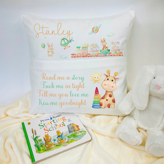 White 40cm cushion with a pocket on the front for a book. The design printed is an animal train in neutral colours. The top part has a name. The bottom part says ‘read me a story, tuck me in tight, tell me you love me, kiss me goodnight.