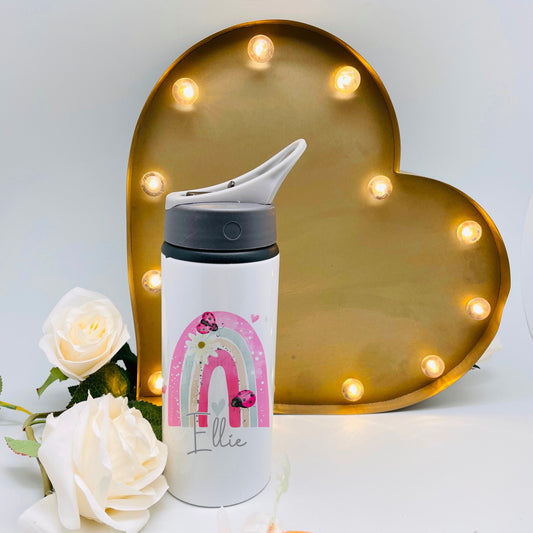 This is a metal flask printed with a pretty pink rainbow with ladybugs on it. The design also features a name at the bottom. The flask has a flip straw opening and a carry handle. This is ideal for school or nursery