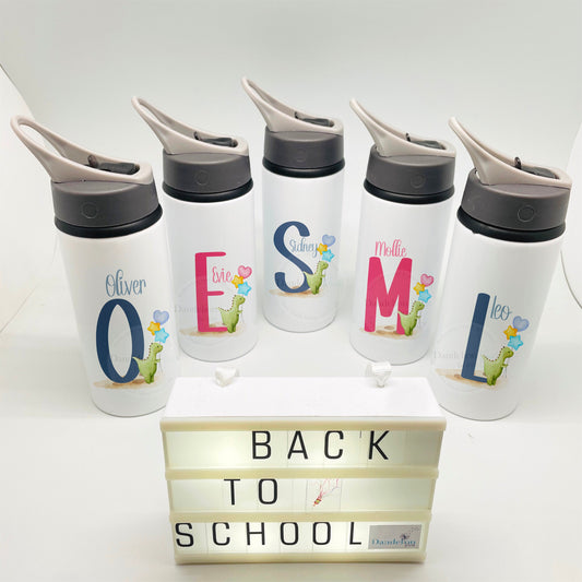 This is a metal school flask with a flip up sports spout. Printed on the flask is a cute watercolour green dinosaur with balloons next to a blue or pink initial. There is a name printed above the Dino. Personalised school lunch bag